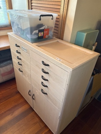 Wooden storage cabinet with millinery contents