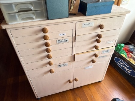 Wooden storage cabinet on casters with contents of sewing materials and magazines