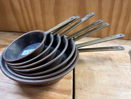 Set of copper gratuated skillets
