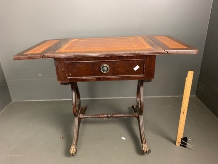 Side table with 2 small drop sides, tan inset leather top with gold embossed borders, single drawer, lyre-shaped supports on stretcher base, on castors