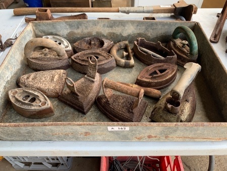 Selection of vintage irons in tin tray