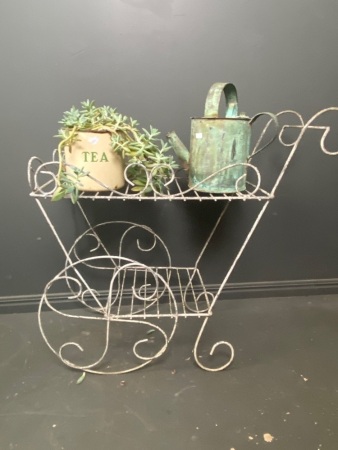 Metal garden plant stand with antique metal watering can and succulent plant in old metal tea tin