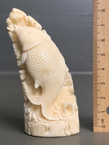 Intricately carved whale tooth carving of a fish (scrimshaw)